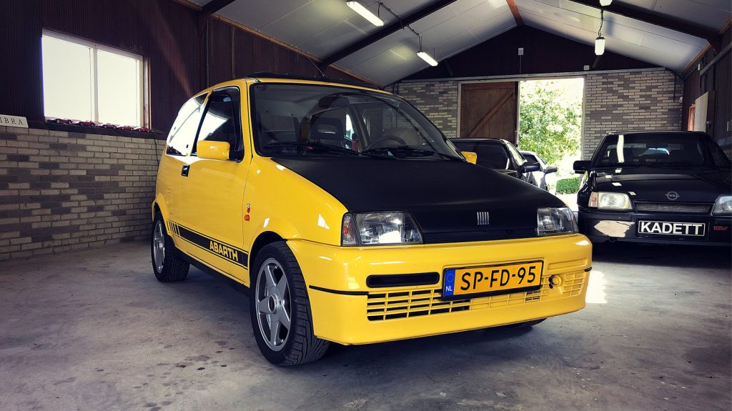 Fiat Cinquecento Sporting, driekwart van voren tegen een donkere gevel