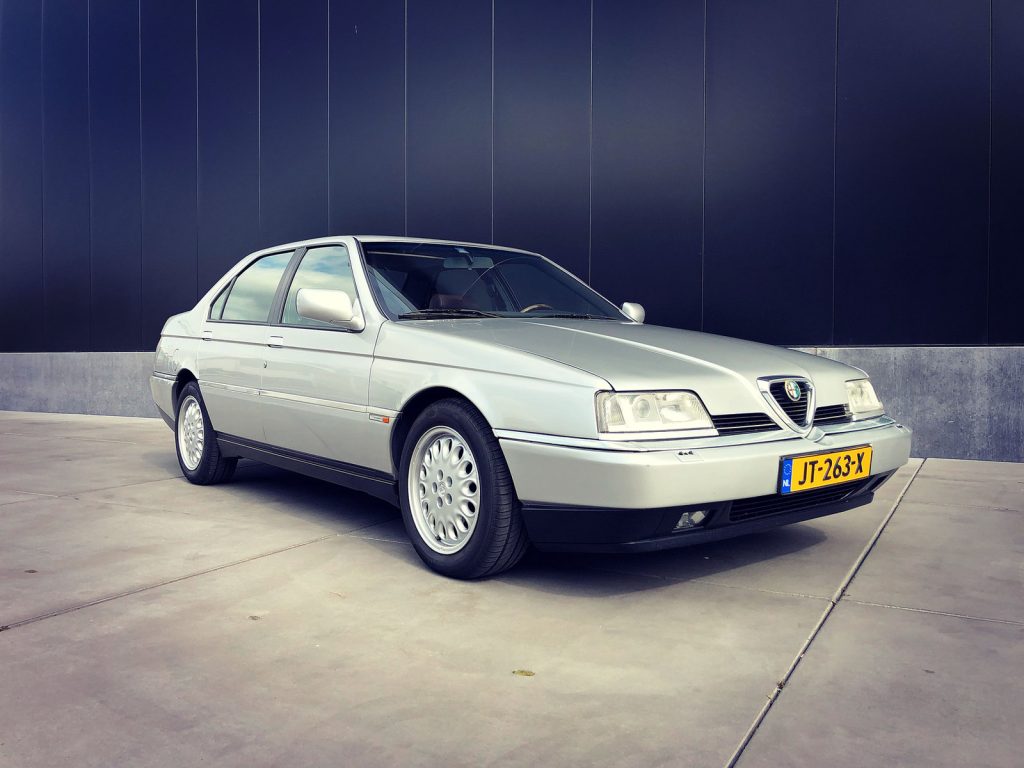 Alfa Romeo 164 Super 3.0 V6 24V, driekwart van voren tegen een donkere gevel