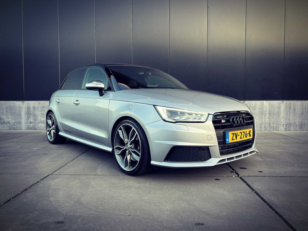 Audi S1 Sportback 2.0 TFSI quattro, driekwart van voren tegen een donkere gevel