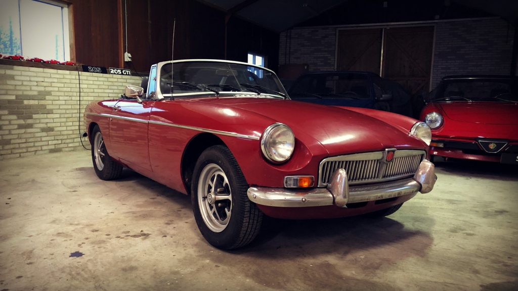MG B Roadster, driekwart van voren tegen een donkere gevel