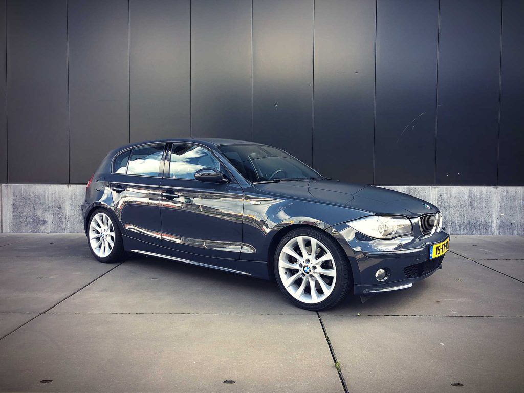 BMW 130i (E87), driekwart van voren tegen een donkere gevel