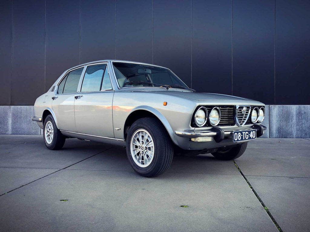 Alfa Romeo Alfetta 1.8 Lusso, driekwart van voren tegen een donkere gevel