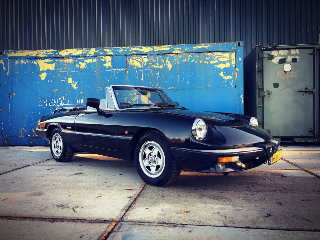 Alfa Romeo Spider 2.0, driekwart van voren tegen een donkere gevel
