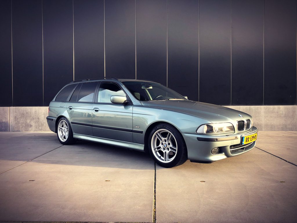 BMW 525i Touring (E39) M-Sport, driekwart van voren tegen een donkere gevel