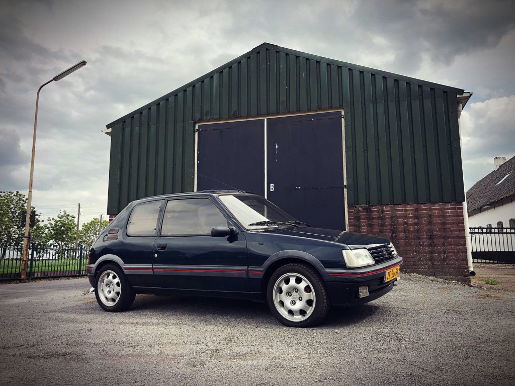 Peugeot 205 GTI 1.9, driekwart van voren tegen een donkere gevel