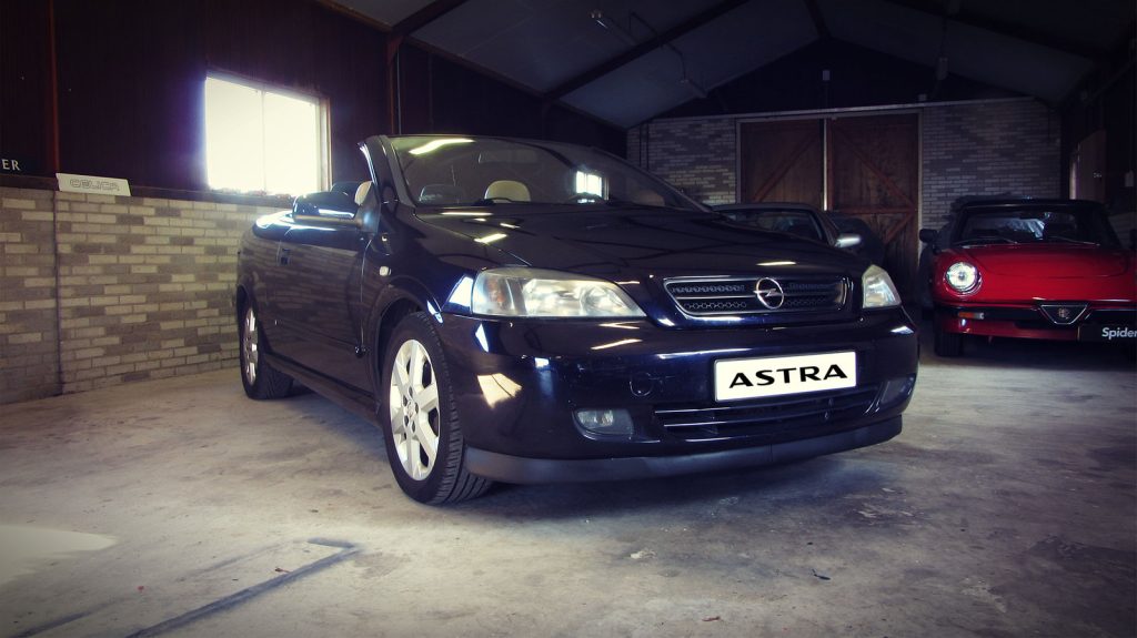 Opel Astra Cabrio 2.2 16V AUT, driekwart van voren tegen een donkere gevel