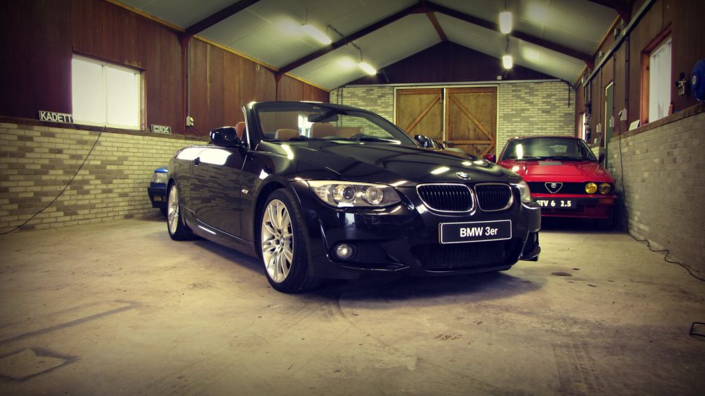 BMW 320d Cabrio (E93) M-Sport, driekwart van voren tegen een donkere gevel