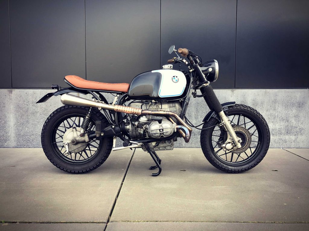 BMW R80/7 Scrambler, driekwart van voren tegen een donkere gevel