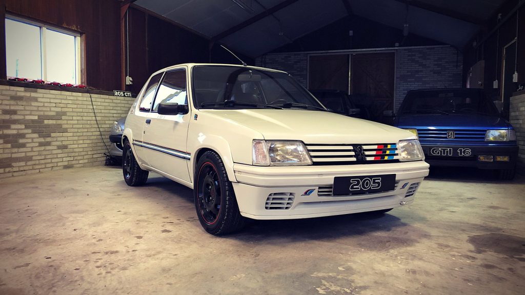 Peugeot 205 Rallye 1.9, driekwart van voren tegen een donkere gevel