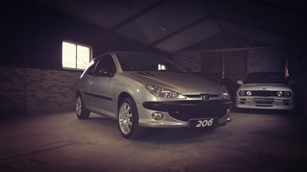 Peugeot 206 GTI 2.0 16V, driekwart van voren tegen een donkere gevel