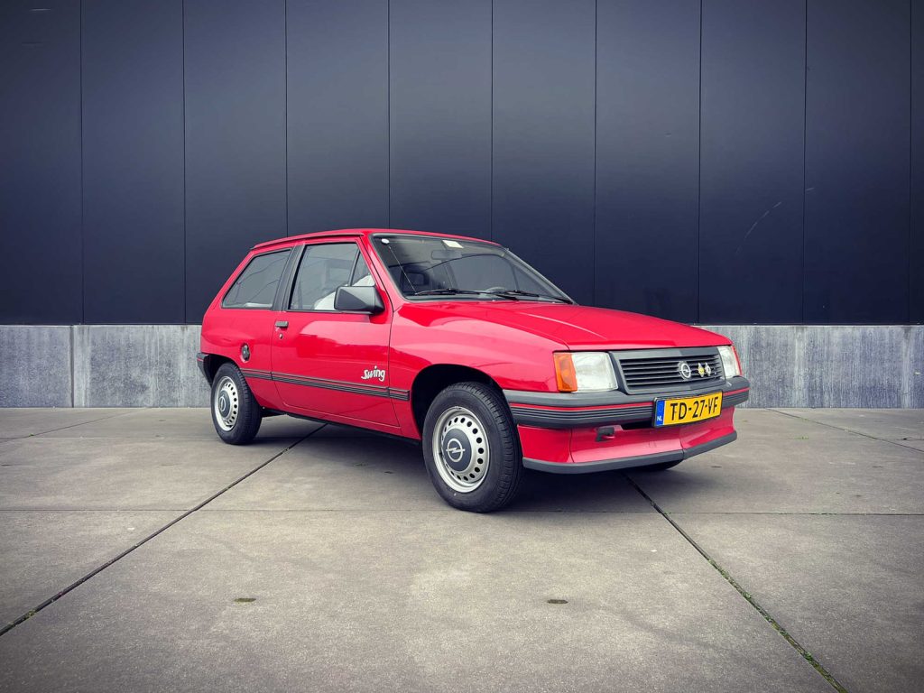 Opel Corsa 1.3 Swing, driekwart van voren tegen een donkere gevel