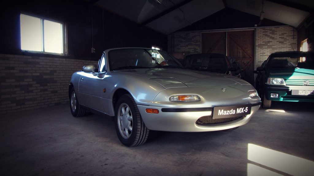 Mazda MX-5 1.6 (NA), driekwart van voren tegen een donkere gevel