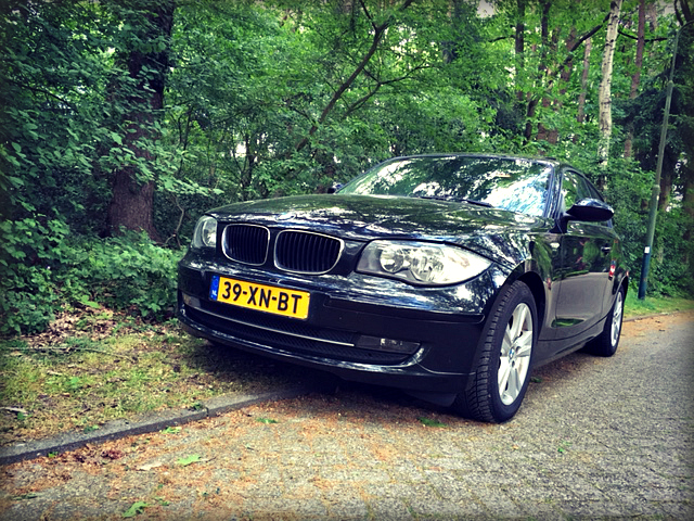 BMW 120i (E87), driekwart van voren tegen een donkere gevel