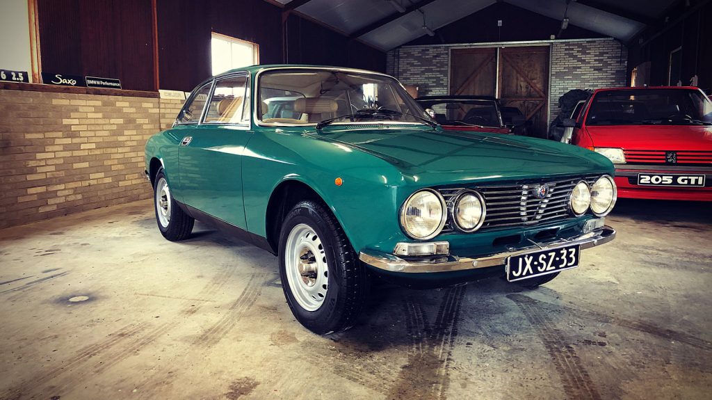 Alfa Romeo GT 1300 Junior, driekwart van voren tegen een donkere gevel
