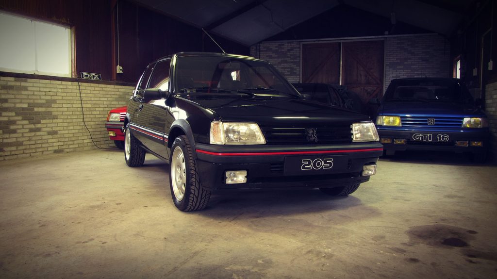 Peugeot 205 GTI 1.9, driekwart van voren tegen een donkere gevel