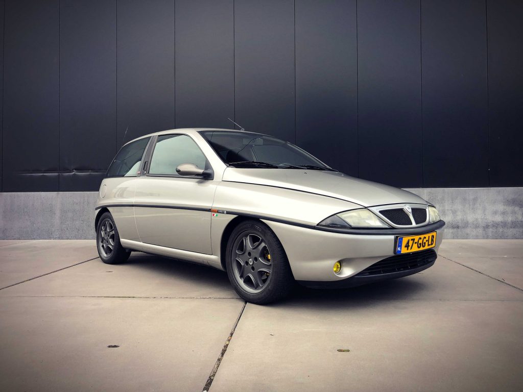 Lancia Ypsilon Elefantino Rosso, driekwart van voren tegen een donkere gevel