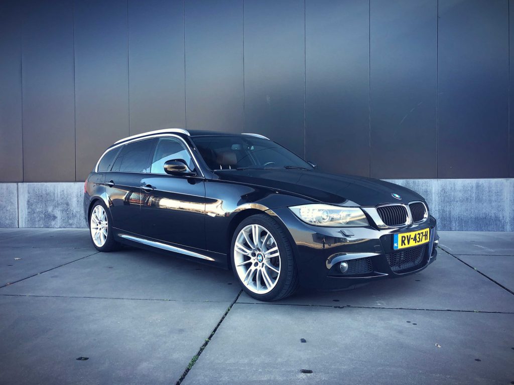 BMW 320d Touring (E91) M-Sport, driekwart van voren tegen een donkere gevel