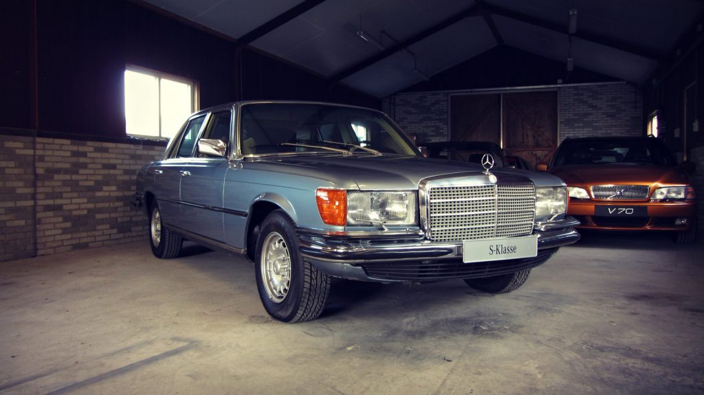 Mercedes-Benz 280 SE (W116), driekwart van voren tegen een donkere gevel
