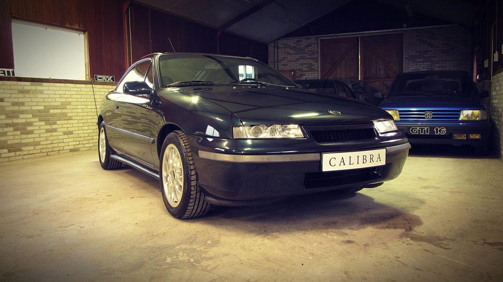 Opel Calibra V6, driekwart van voren tegen een donkere gevel