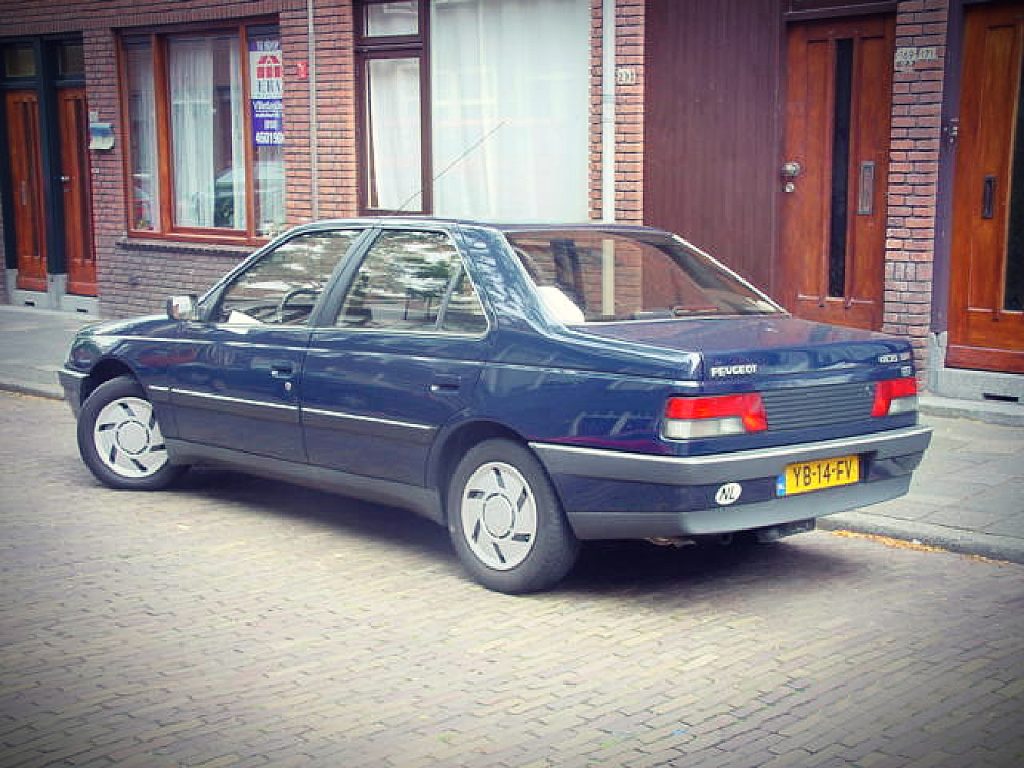 Peugeot 405 SRi 1.9, driekwart van voren tegen een donkere gevel