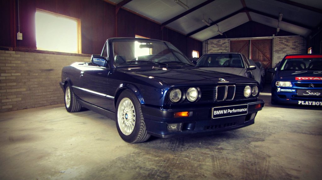 BMW 325i Cabrio (E30), driekwart van voren tegen een donkere gevel