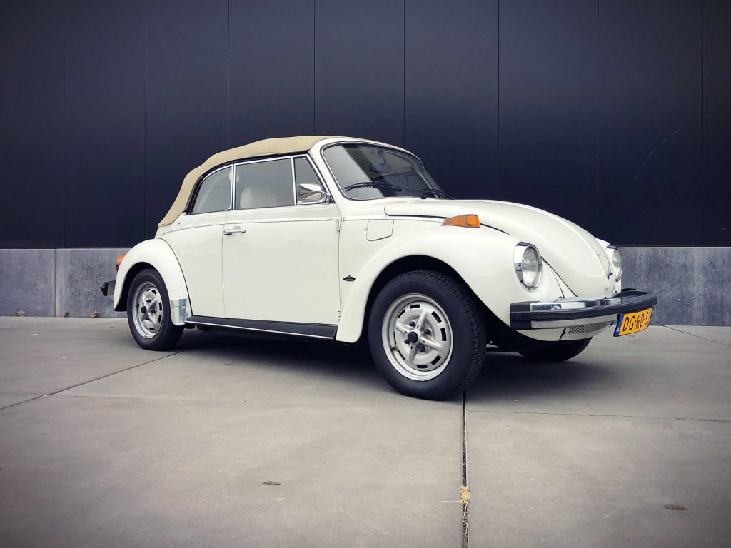 Volkswagen Kever Cabriolet, driekwart van voren tegen een donkere gevel