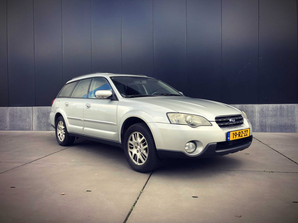Subaru Outback 2.5i Aut., driekwart van voren tegen een donkere gevel