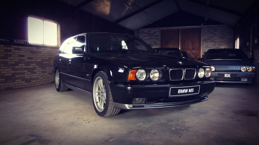BMW M5 Touring (E34), driekwart van voren tegen een donkere gevel