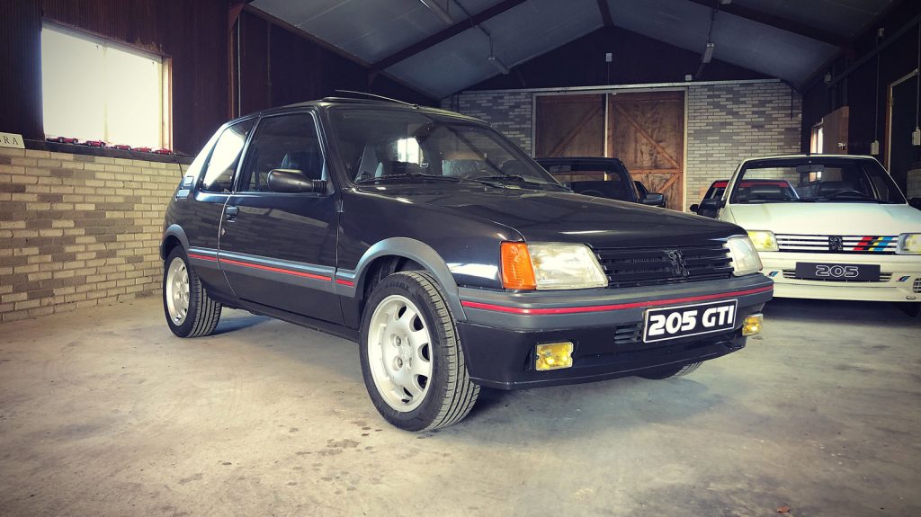 Peugeot 205 GTI 1.9 (130pk), driekwart van voren tegen een donkere gevel