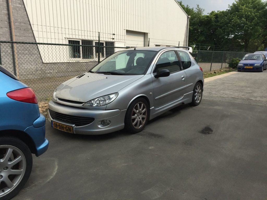 Peugeot 206 GT (Grand Tourisme), driekwart van voren tegen een donkere gevel