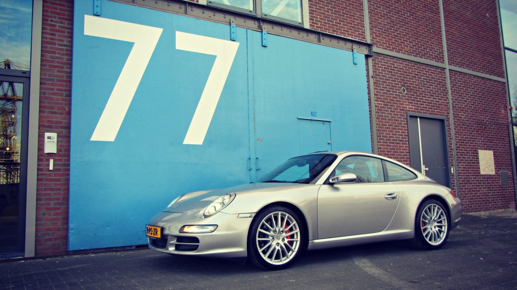 Porsche 911 3.8 Carrera S (997), driekwart van voren tegen een donkere gevel