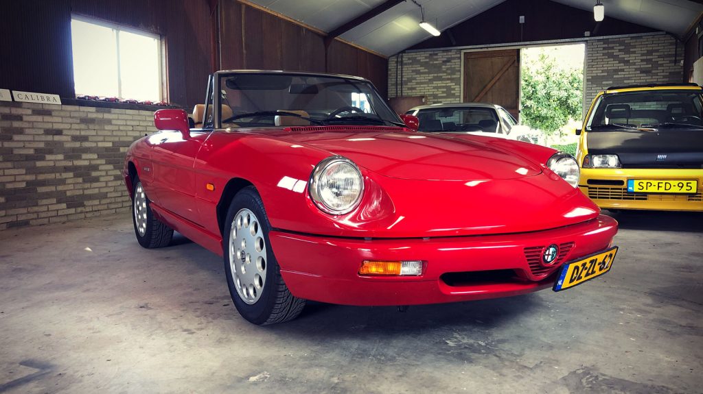 Alfa Romeo Spider 2.0, driekwart van voren tegen een donkere gevel
